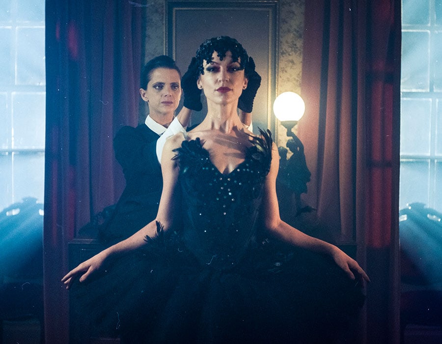 Two performers in an elaborately staged, blue-lit interior